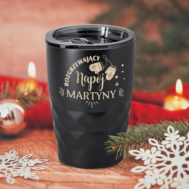 Czarny, matowy kubek termiczny z napisem "Rozgrzewający napój + imię" i ilustracją zimowych rękawiczek. Dolna część kubka ma geometryczną strukturę.