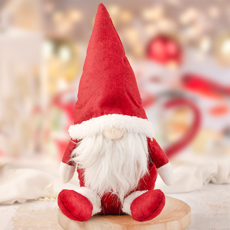 Dekoracyjny pluszowy skrzat w czerwonej czapce i z białą brodą – idealny do świątecznych aranżacji.