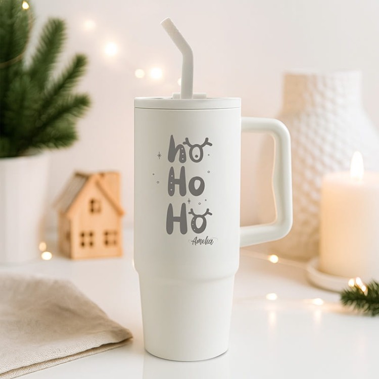 Biały kubek z matowym wykończeniem i świąteczną grafiką w zimowej aranżacji.