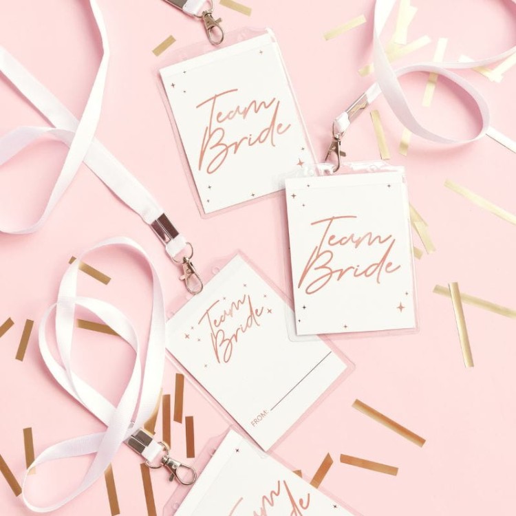 Białe identyfikatory na wieczór panieński z napisem Team Bride na różowym tle z konfetti.
