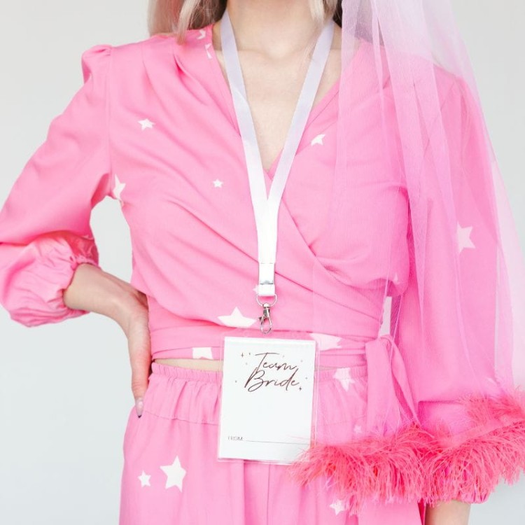 Białe karty Team Bride w przezroczystych etui z metalowymi zapięciami na wieczór panieński.