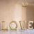 Złoty balon foliowy tworzący napis LOVE ustawiony w jednym rzędzie jako dekoracja ślubna.