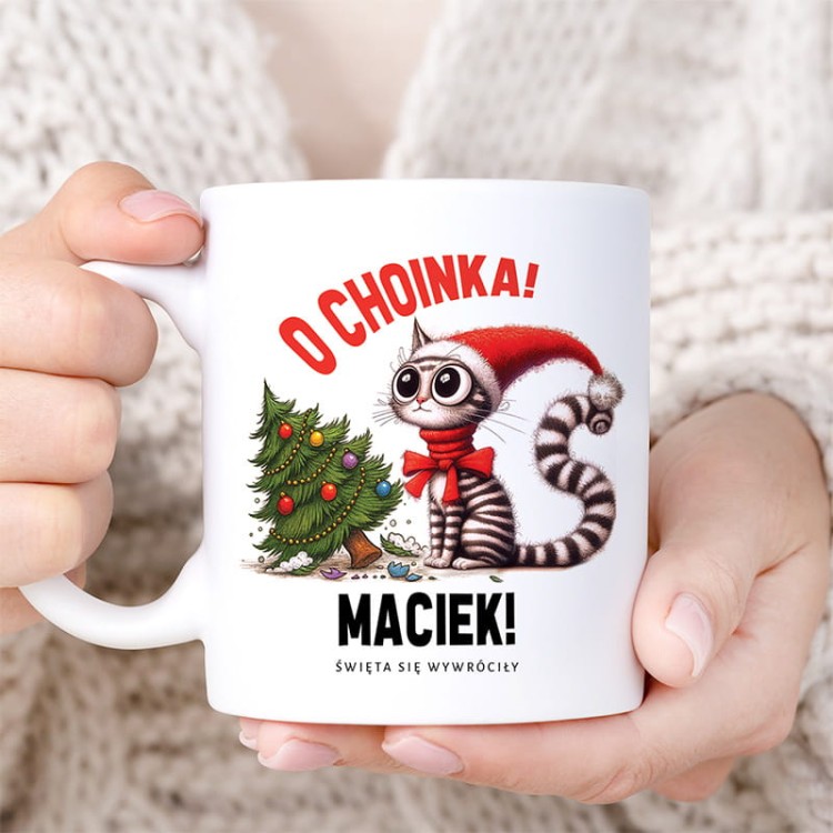Kubek świąteczny z ilustracją kota i przewróconą choinką.