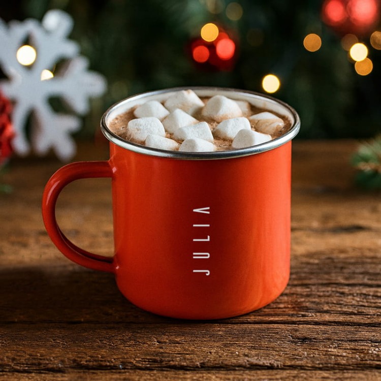 Czerwony metalowy kubek z nadrukiem Świętego Mikołaja na tle choinki