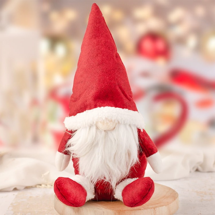 Gotowy kosz prezentowy z pluszowym skrzatem, świecą i słodkościami w świątecznym klimacie.