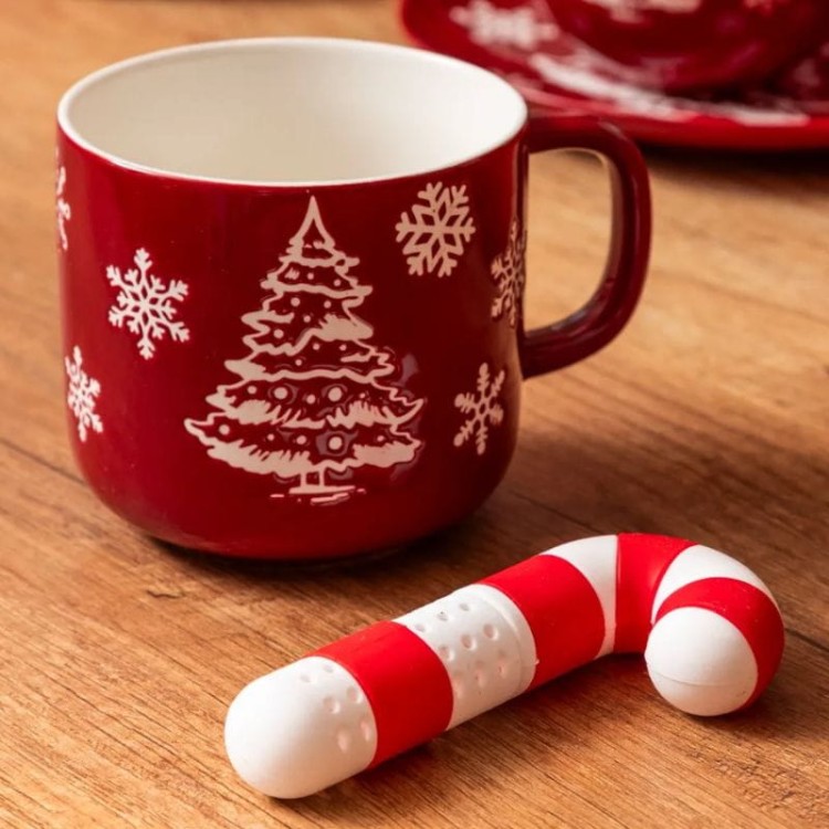 Świąteczny zaparzacz do herbaty w kształcie laski cukrowej na drewnianym stole.