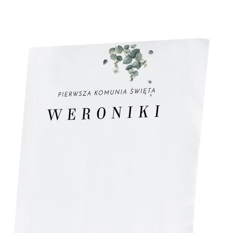 Biały pokrowiec na Pierwszą Komunię Świętą z nadrukiem i dekoracyjnym motywem roślinnym.