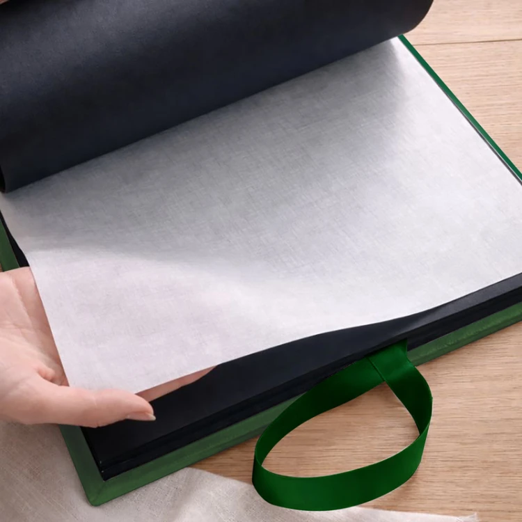 Album z czarnymi stronami przełożonymi pergaminem.