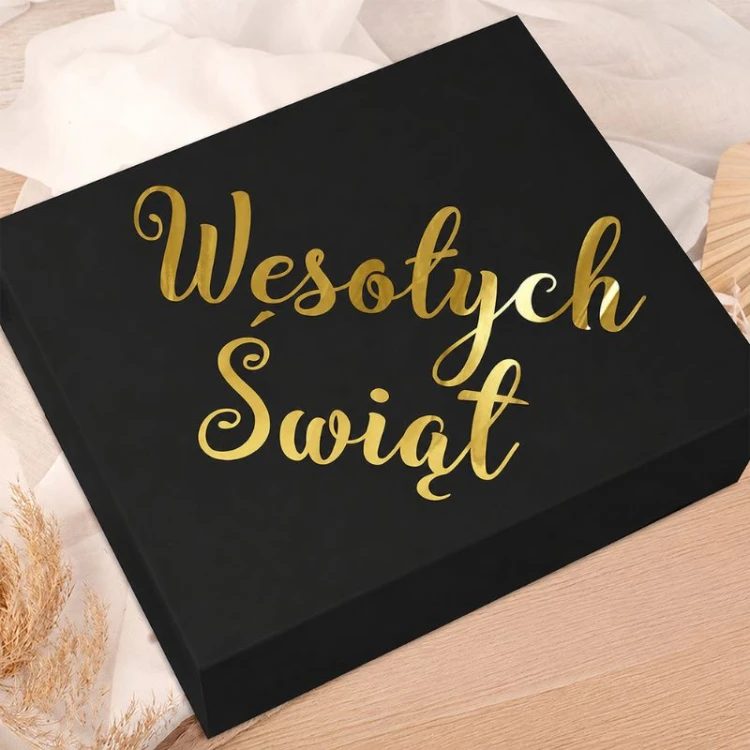 Czarne pudełko prezentowe z ozdobnym złotym napisem „Wesołych Świąt” na wieczku. Eleganckie opakowanie idealne na świąteczny upominek.