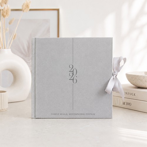 Elegancki album na wspomnienia z personalizacją roku ustawiony we wnętrzu w jasnej aranżacji.
