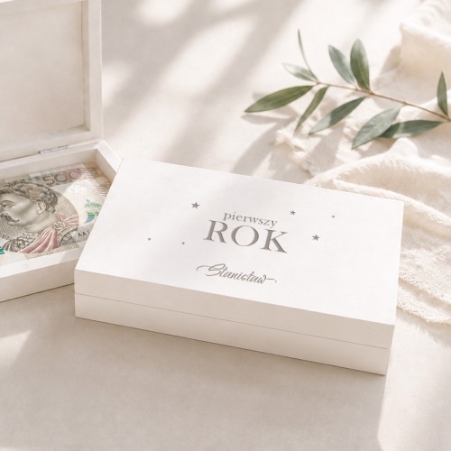 Drewniane pudełko na pieniądze na roczek leży obok otwartego pudełka z banknotami.