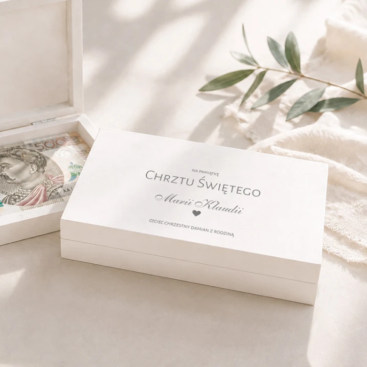Drewniane pudełko na pieniądze na chrzest leży obok otwartego pudełka z banknotem.