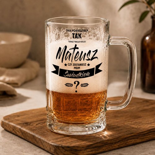 Personalizowany kufel do piwa z napisem „Ona powiedziała TAK. Mateusz, czy zostaniesz moim świadkiem?” na drewnianej desce w jasnej aranżacji.