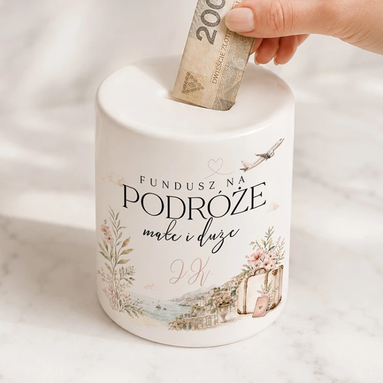 Ceramiczna skarbonka dla podróżniczki ma napis „Fundusz na podróże małe i duże”.