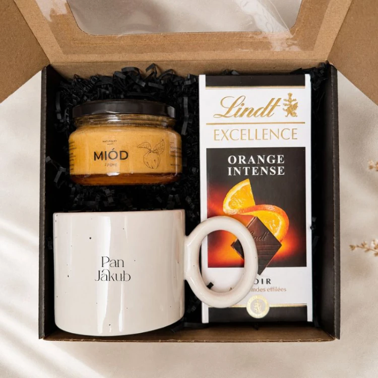 Elegancki zestaw prezentowy dla nauczyciela zawiera personalizowany kubek, czekoladę Lindt i smakowy miód.