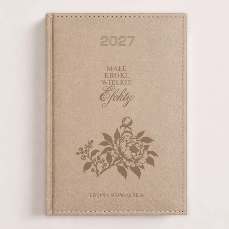 Personalizowany kalendarz książkowy 2027 z imieniem i motywacyjnym kwiatowym wzorem na beżowej okładce.