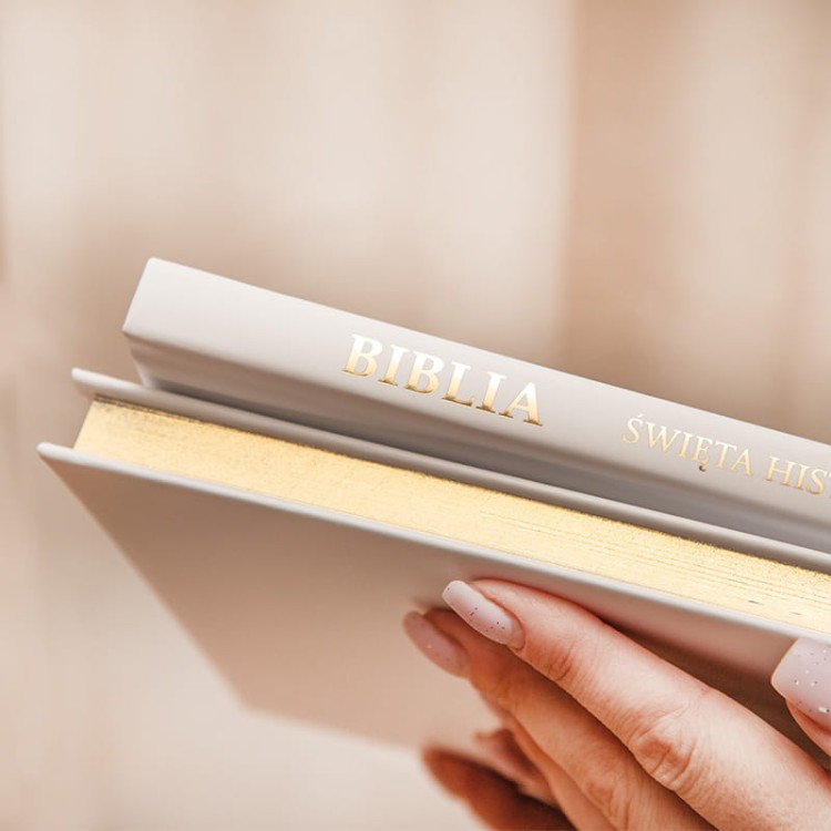 Biblia ze złoconymi brzegami na komunię z eleganckim napisem na grzbiecie.